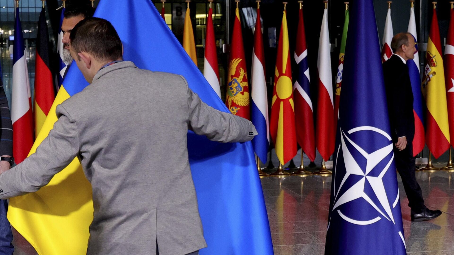 Офицер протокола поправляет украинский флаг в штаб-квартире НАТО в Брюсселе