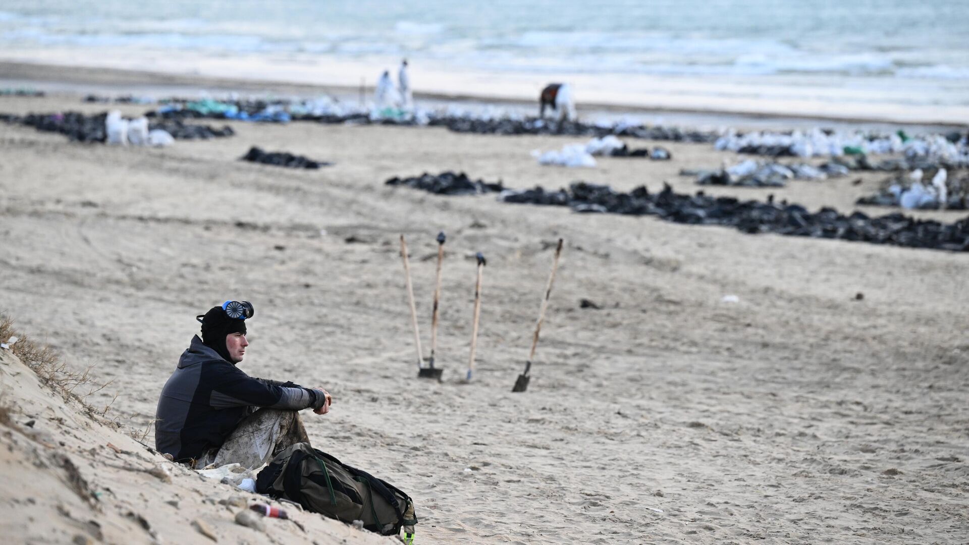 Волонтер, участвующий в уборке мазута на пляже детского лагеря