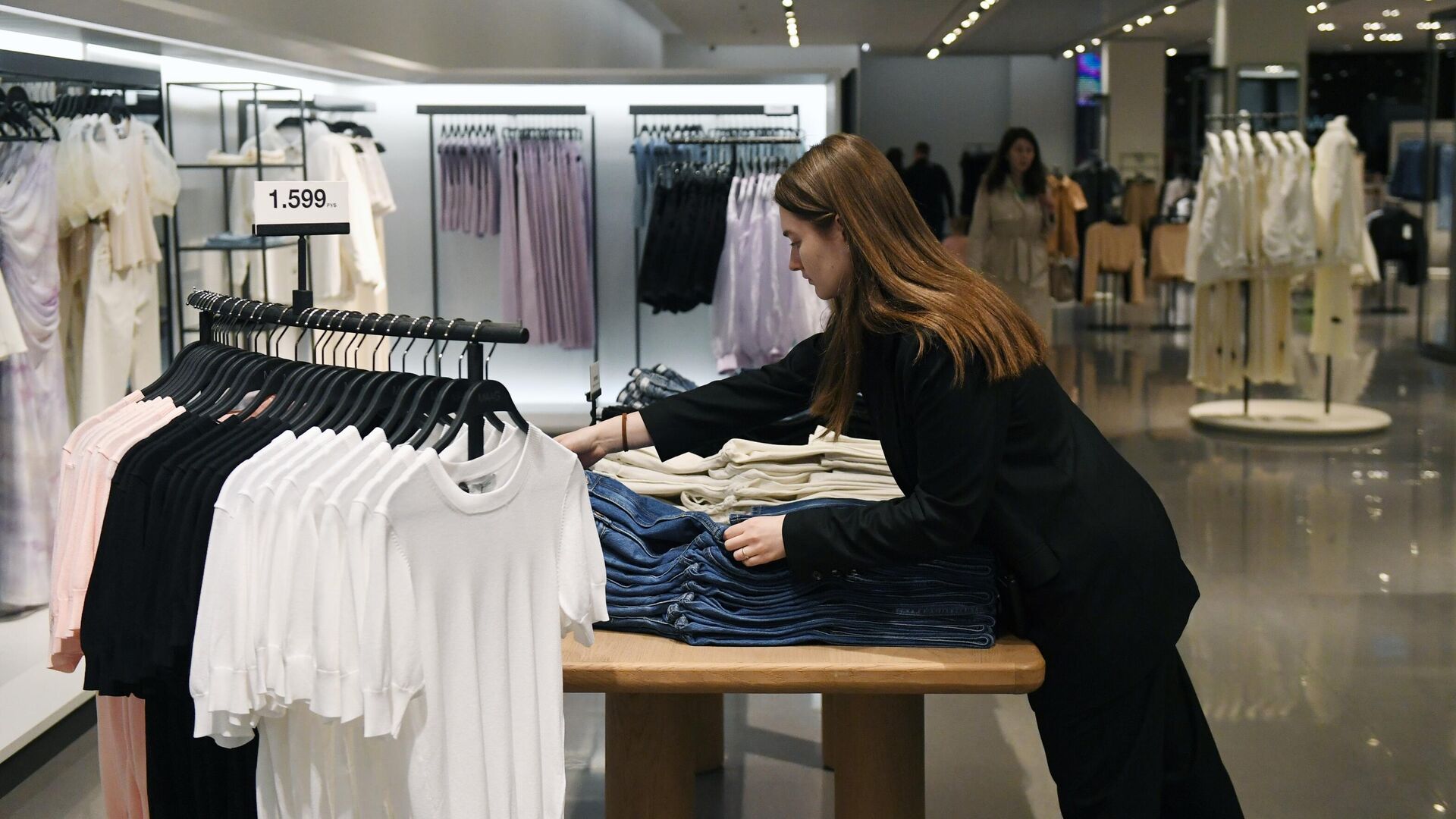 Продавец раскладывает одежду в магазине