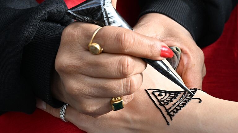 Нанесение временных узоров на кожу с помощью натуральной хны на 10-м фестивале День Индии в Южном ландшафтном парке Остров Мечты в Москве