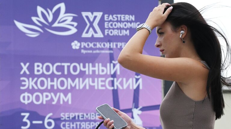Девушка на фоне баннера Восточного экономического форума на улице Светланская во Владивостоке