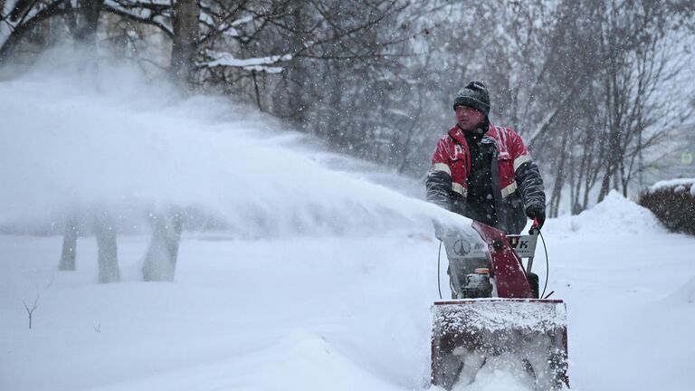 Сотрудник коммунальных служб убирает снег на улице в Москве