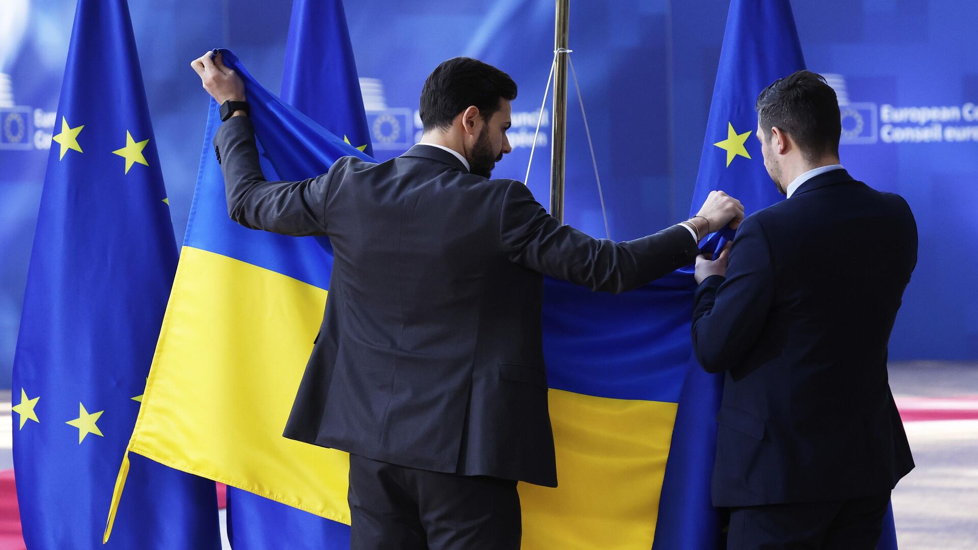 Сотрудники службы протокола вывешивают флаг Украины перед приездом Владимира Зеленского в Брюссель