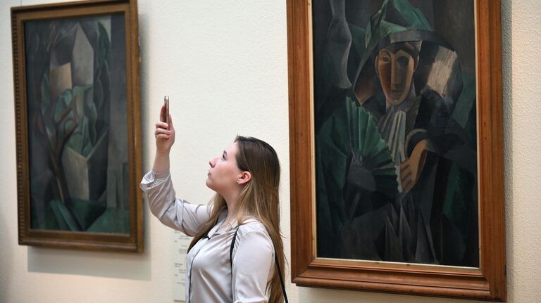 Журналист около картины художника П.Пикассо Дама с веером на пресс-показе фокус-выставки Матисс и Пикассо. Цвет и форма в Третьяковской галерее